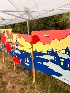 Panneaux peints lors de l'atelier participatif à la Fête du Sarrasin à Saint-Coulomb : décor de bord de mer breton en couleurs pop, phare, bateau et maisons